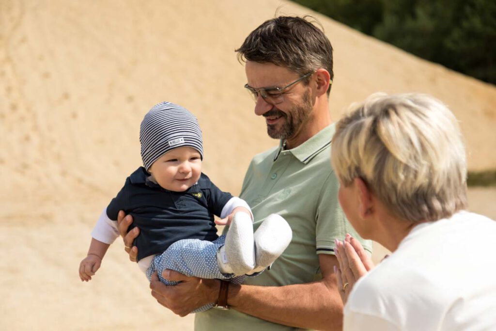 Jan Windisch, Fotograf und Hochzeitsfotograf aus Dresden, Prina, Görlitz, Großenhain und Leipzig, hat hier eine Familie mit einem Kind fotografiert. Der Vater trägt das Kind mit beiden Armen und die Frau schaut dem Kind in die Augen.