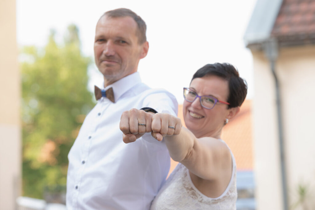 Jan Windisch, Fotograf und Hochzeitsfotograf aus Dresden, Prina, Görlitz, Großenhain und Leipzig, hat hier ein Brautpaar fotografiert. Das Paar steht nebeneinander und strecken jeweils ihren linken Arm in die Kamera. Beide präsentieren hierbei ihren Verlobungsring.