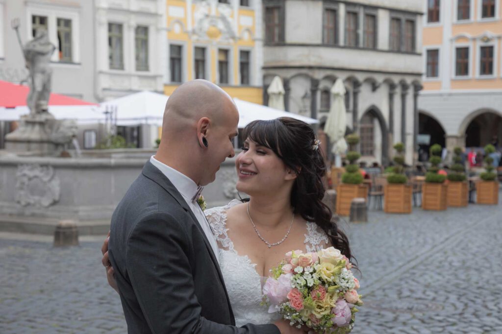 Brautpaar schaut sich nach der standesamtlichen Trauung im Rathaus glücklich auf dem Markt an.
